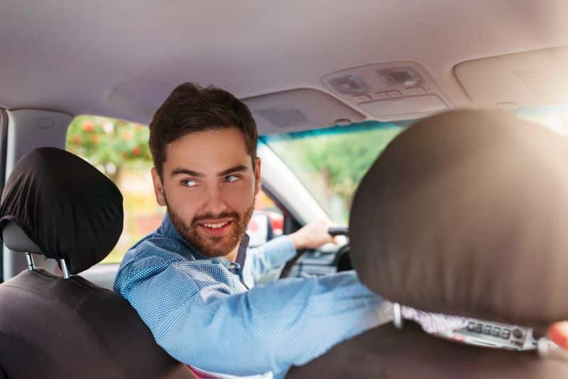 Driver seated behind the wheel looking back inside a car, representing reliable car hire in Rockingham 6168.